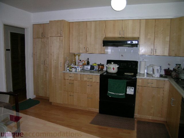 Bright kitchen with light wood cabinets, black appliances, and hardwood floors. - 4408 Arbutus Street, Vancouver West Side