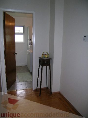 Framed hallway leading to bathroom with wooden door and hardwood floors. - 4408 Arbutus Street, Vancouver West Side