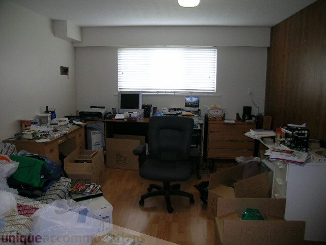 Living room with cluttered furniture and boxes, hardwood floors. - 4408 Arbutus Street, Vancouver West Side