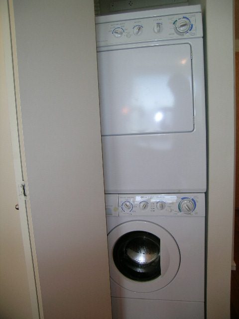 Bright laundry room with stacked washer and dryer, clean white surfaces. - 1102 - 1723 Alberni Street, Vancouver Downtown