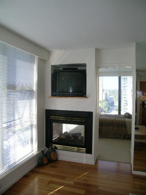 Bright living room with hardwood floors, city view, and a modern fireplace. - 1102 - 1723 Alberni Street, Vancouver Downtown