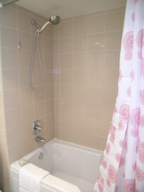 Bright bathroom with pink tile and patterned shower curtain. - 1102 - 1723 Alberni Street, Vancouver Downtown