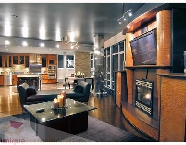 Modern living room with sleek furniture, hardwood floors, and a large TV setup. - 3202 - 1483 Homer Street, Vancouver Downtown
