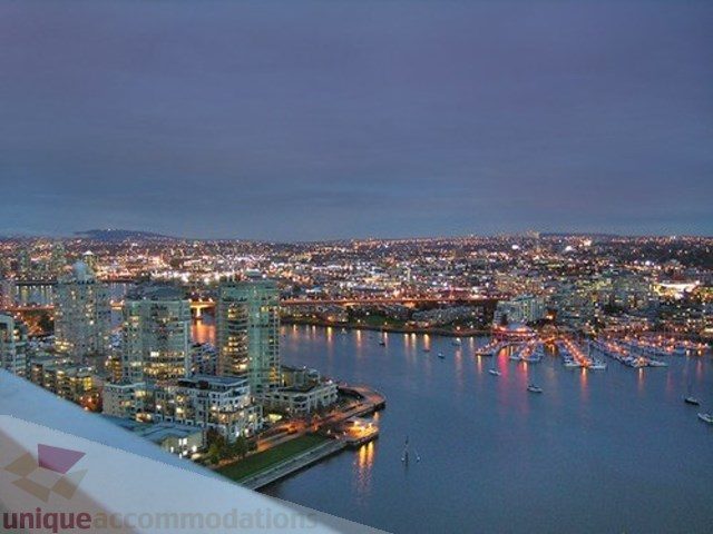 Bright kitchen with city view and waterfront access, showcasing vibrant downtown lights and water reflections.