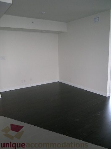 Bright living room with dark hardwood floors and built-in shelving. - 2804-788 Richards Street, Vancouver Downtown
