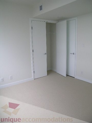 Bright and spacious bedroom with ample closet space and neutral carpeting. - 2804-788 Richards Street, Vancouver Downtown