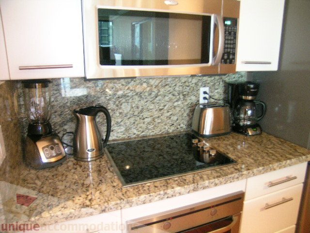 Bright kitchen with granite countertops, stainless steel appliances, and a modern microwave. - 1205 - 1331 West Georgia Street, Vancouver Downtown