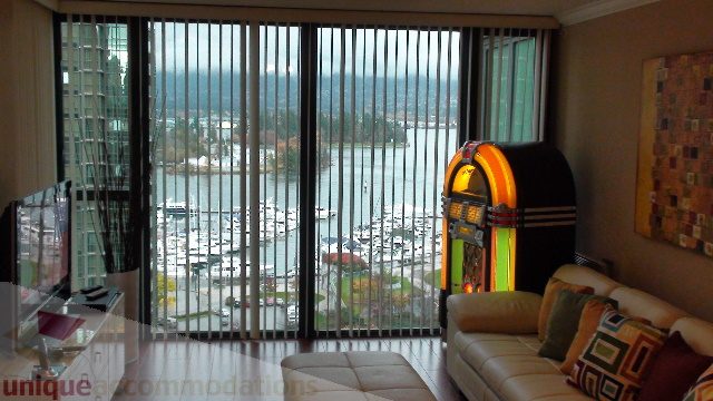 Spacious living room with a vibrant jukebox and stunning city waterfront view. - 1205 - 1331 West Georgia Street, Vancouver Downtown