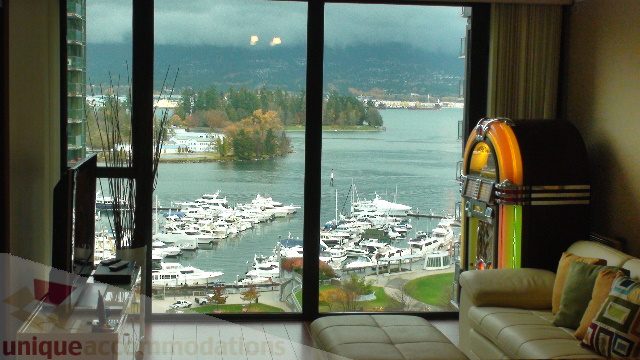 Spacious living room with a stunning city view, featuring a retro jukebox and cozy seating. - 1205 - 1331 West Georgia Street, Vancouver Downtown