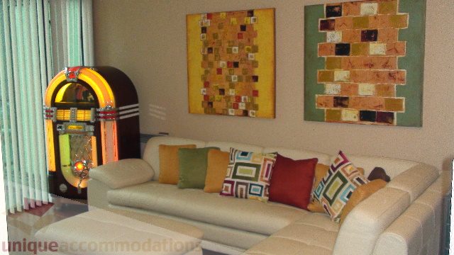 Cozy living room with retro jukebox and colorful wall art, perfect for a 1-bedroom + den condo. - 1205 - 1331 West Georgia Street, Vancouver Downtown