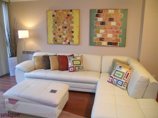 Spacious living room with modern white sectional, colorful pillows, and abstract wall art. - 1205 - 1331 West Georgia Street, Vancouver Downtown