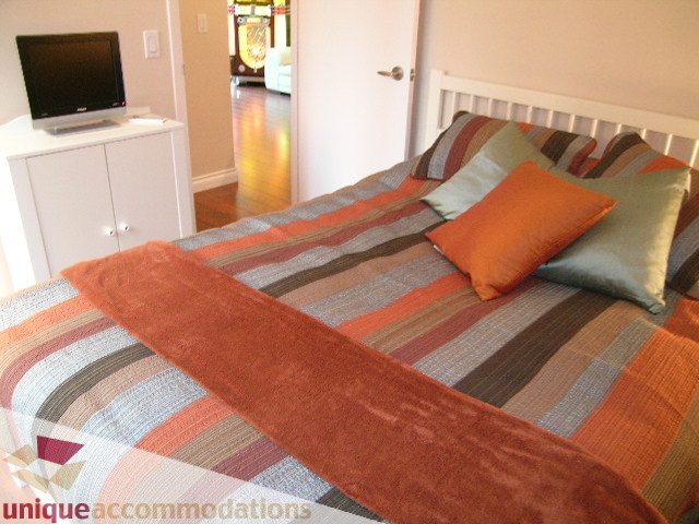 Cozy bedroom with striped bedding and a flat-screen TV, perfect for a comfortable stay. - 1205 - 1331 West Georgia Street, Vancouver Downtown