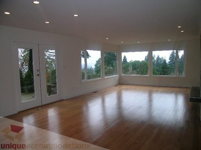 Bright living room with hardwood floors and large windows offering a scenic view. - 250 Rockland Road West, North Vancouver