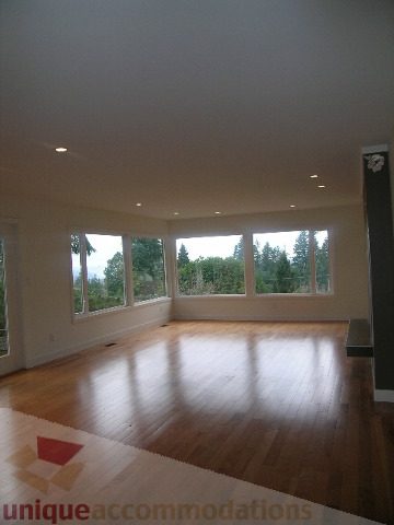 Bright living room with hardwood floors and large windows showing a city view. - 250 Rockland Road West, North Vancouver