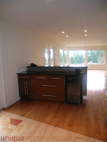 Bright kitchen with black countertops and hardwood floors, city view through large windows. - 250 Rockland Road West, North Vancouver