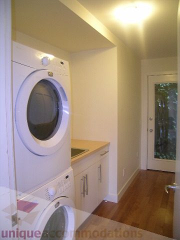 Bright laundry room with white cabinets, hardwood floors, and a city view. - 250 Rockland Road West, North Vancouver