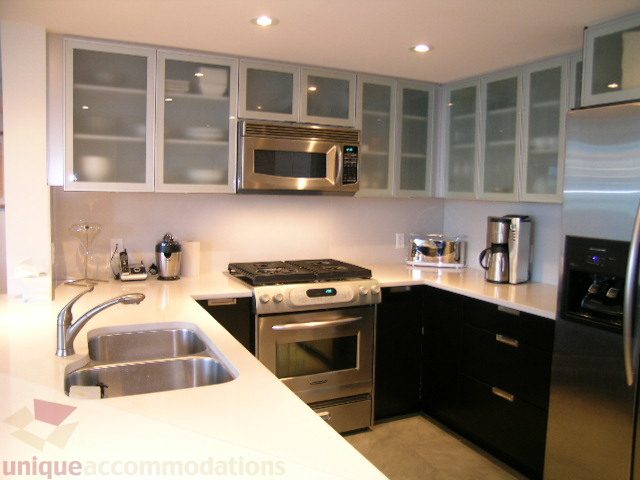 Bright kitchen with sleek white countertops, stainless steel appliances, and modern cabinetry. - 604 - 1205 West Hastings Street, Vancouver Downtown