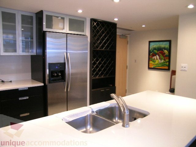 Bright kitchen with sleek white countertops, modern sink, and wine rack. - 604 - 1205 West Hastings Street, Vancouver Downtown