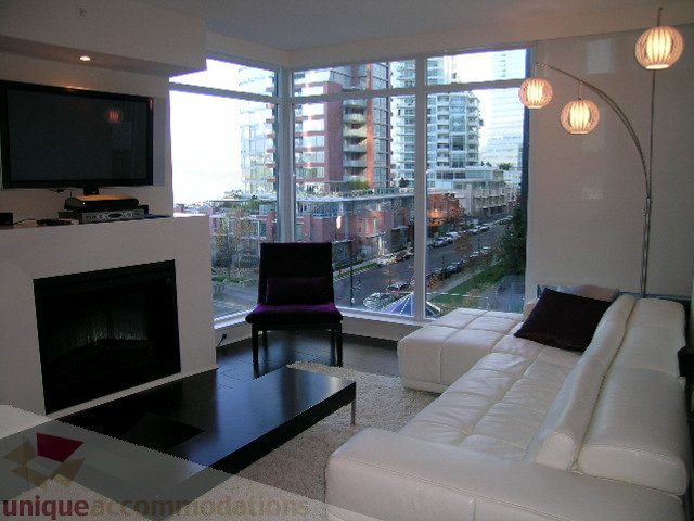Bright living room with modern furniture, city view, and large windows. - 604 - 1205 West Hastings Street, Vancouver Downtown