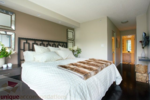 Spacious bedroom with a king-sized bed, fur throw, and modern decor. - Townhouse 117 - 118 Drake Street, Vancouver Downtown
