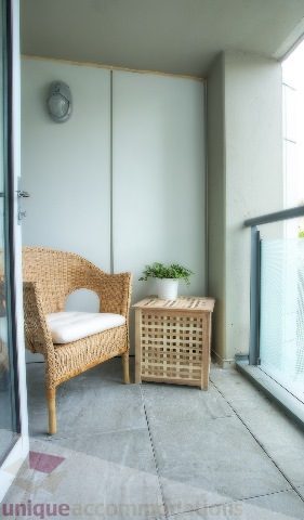 Furnished balcony with wicker chair, small table, and potted plant. - Townhouse 117 - 118 Drake Street, Vancouver Downtown
