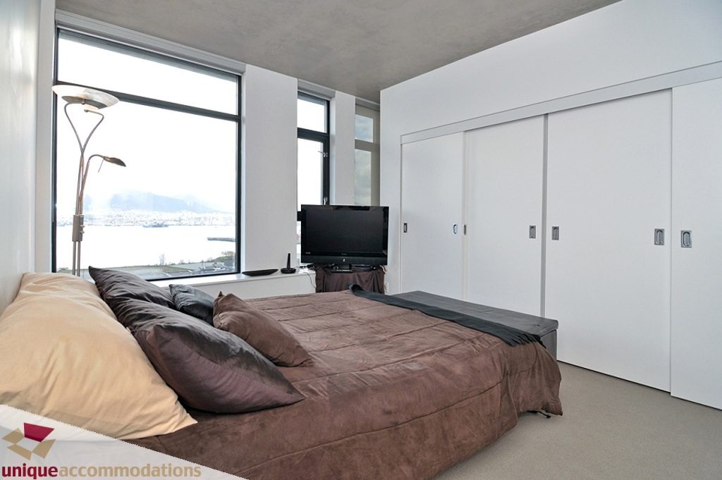 Spacious 2-bedroom condo with modern furnishings, large windows offering a city view, and sleek white cabinetry.