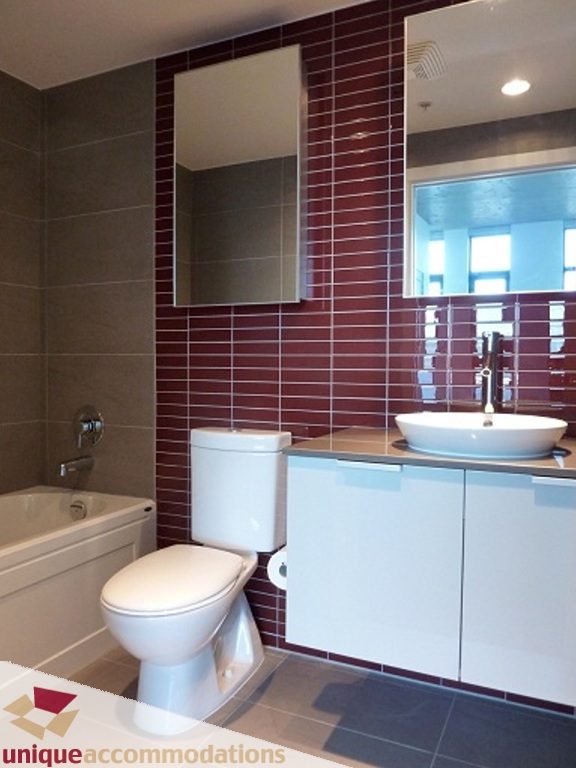 Modern bathroom with red tile accent wall and white countertop sink. - 1409 - 108 West Cordova, Vancouver Downtown