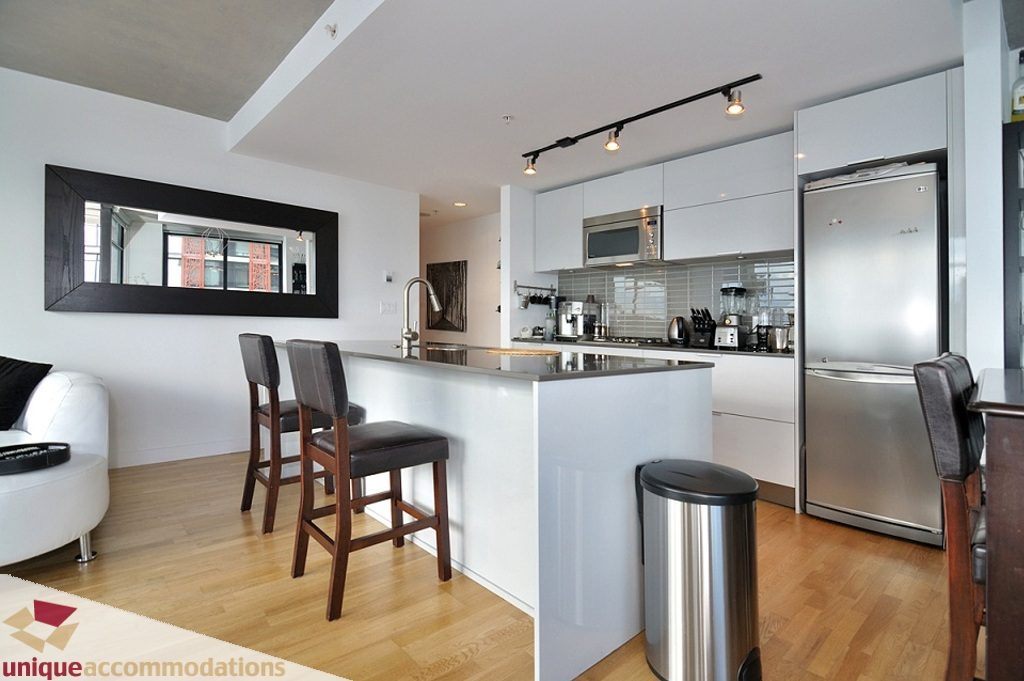 Bright kitchen with modern stainless steel appliances, hardwood floors, and a large window view. - 1409 - 108 West Cordova, Vancouver Downtown