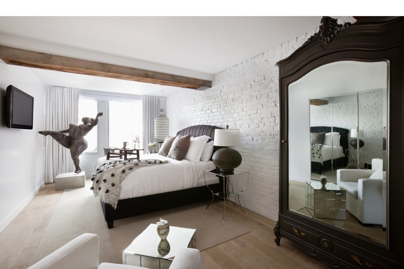 Bright bedroom with white brick wall, large mirror, and modern decor. - 30 - 133 Keefer Street, Vancouver Downtown