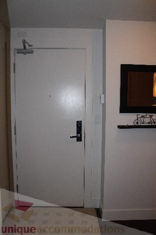 Bright entryway with white door and mounted TV. - 705 - 565 Smithe Street, Vancouver Downtown