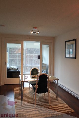 Furnished dining area with hardwood floors and a striped rug, leading to a balcony with a city view. - 705 - 565 Smithe Street, Vancouver Downtown