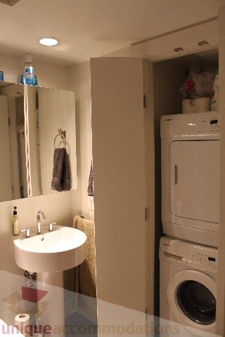 Compact bathroom with white sink and countertop, adjacent laundry area. - 705 - 565 Smithe Street, Vancouver Downtown