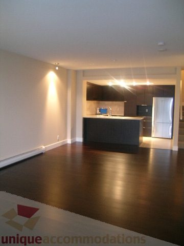 Spacious living room with dark hardwood floors and modern furnishings. - 1309 Civic Place Mews, North Vancouver