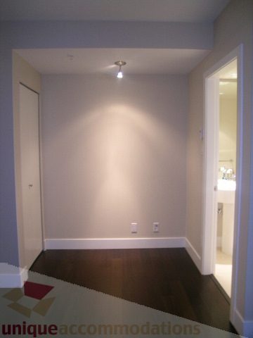 Spacious living room with hardwood floors and a modern ceiling light fixture. - 1309 Civic Place Mews, North Vancouver