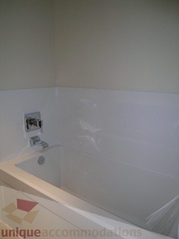 Modern bathroom with sleek white fixtures and tiled walls. - 1309 Civic Place Mews, North Vancouver