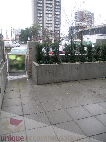 Furnished patio with tiled flooring and a small garden area, overlooking a cityscape. - 1309 Civic Place Mews, North Vancouver