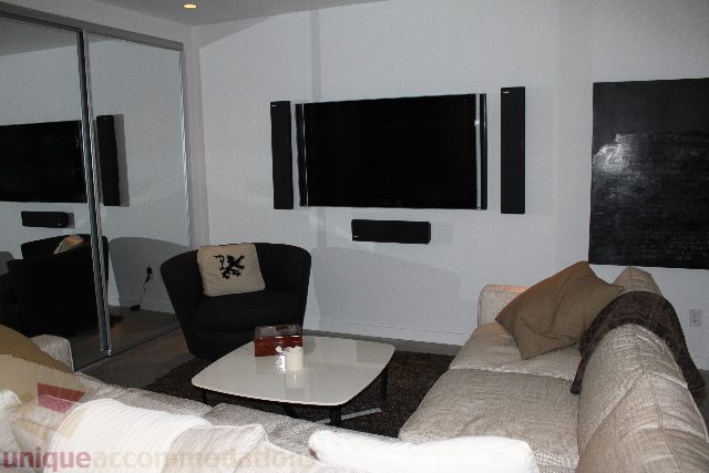 Living room with modern furniture, flat-screen TV, and large windows. - 701 - 546 Beatty Street, Vancouver Downtown