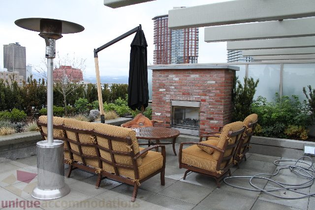 Furnished rooftop patio with brick fireplace, outdoor seating, and city view. - 701 - 546 Beatty Street, Vancouver Downtown