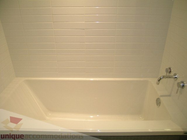 Bathroom with white tiled walls and a bathtub with chrome fixtures. - 216 - 388 West 1st Avenue, Vancouver West Side