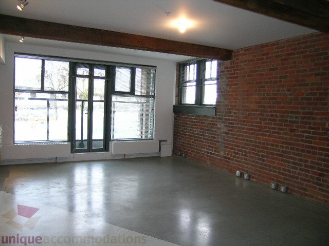 Bright living room with exposed brick wall and large windows, concrete floors. - 216 - 388 West 1st Avenue, Vancouver West Side