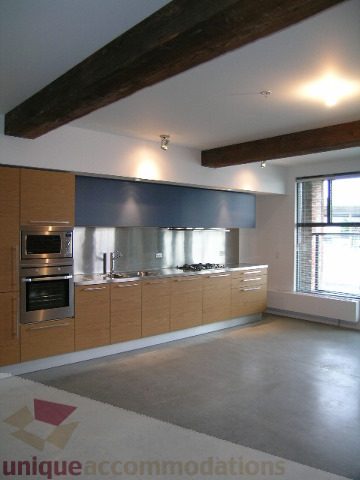 Bright kitchen with stainless steel appliances, concrete countertops, and exposed wooden beams. - 216 - 388 West 1st Avenue, Vancouver West Side