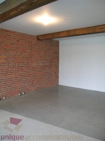 Bright living room with exposed brick wall and concrete floor. - 216 - 388 West 1st Avenue, Vancouver West Side