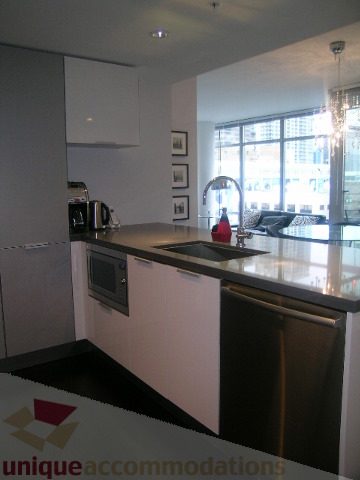 Bright kitchen with sleek white countertops and a city view through large windows. - 1106 - 788 Richards Street, Vancouver Downtown