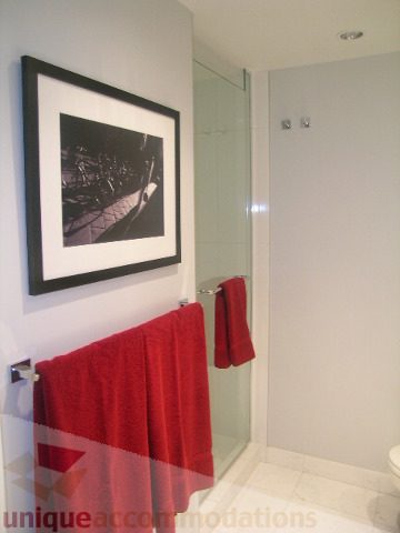 Furnished bathroom with red towels and framed art, modern shower. - 1106 - 788 Richards Street, Vancouver Downtown