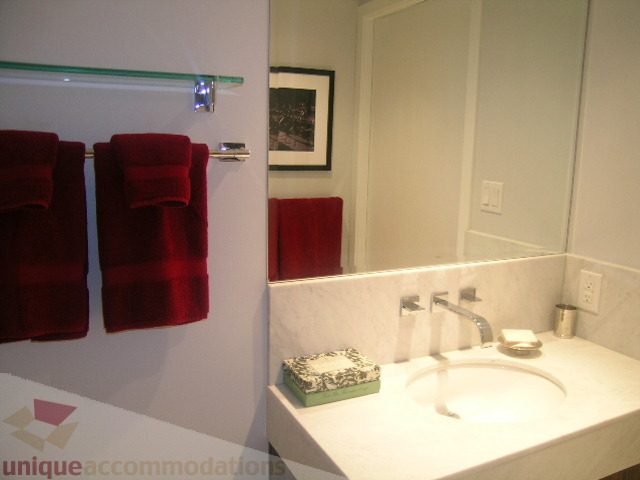 Bathroom with white countertop, red towels, and framed artwork. - 1106 - 788 Richards Street, Vancouver Downtown