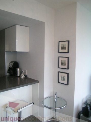 Bright kitchen with modern white cabinetry and sleek countertop, framed artwork on wall. - 1106 - 788 Richards Street, Vancouver Downtown