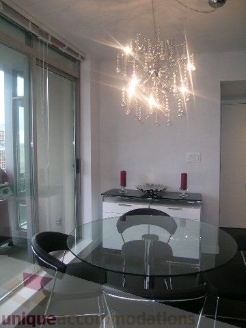 Furnished dining area with a modern chandelier and glass table, city view through sliding doors. - 1106 - 788 Richards Street, Vancouver Downtown