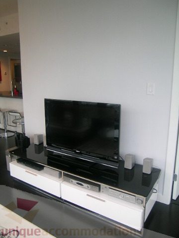 Living room with sleek black TV stand, modern speakers, and minimalist decor. - 1106 - 788 Richards Street, Vancouver Downtown
