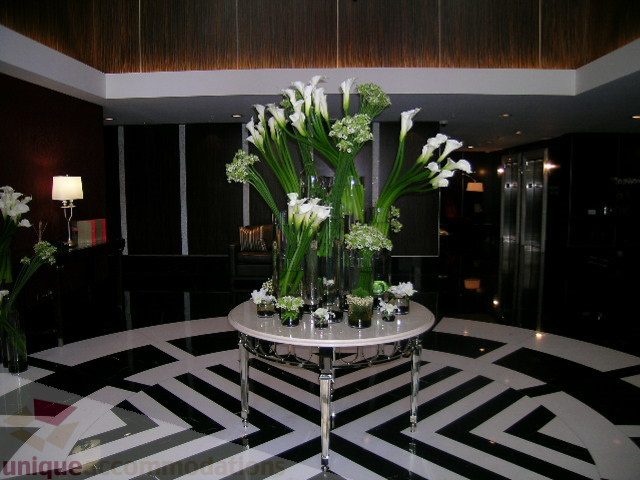 Furnished living room with modern decor, black-and-white patterned floor, and elegant floral arrangements.