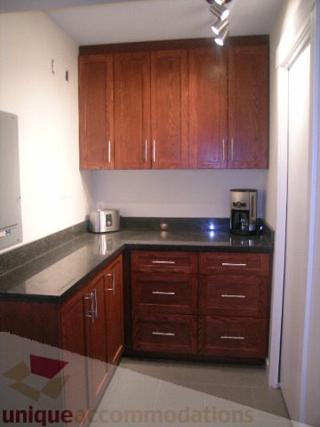 Bright kitchen with dark wood cabinets, granite countertops, and stainless steel appliances. - 907 - 1189 Melville Street, Vancouver Downtown